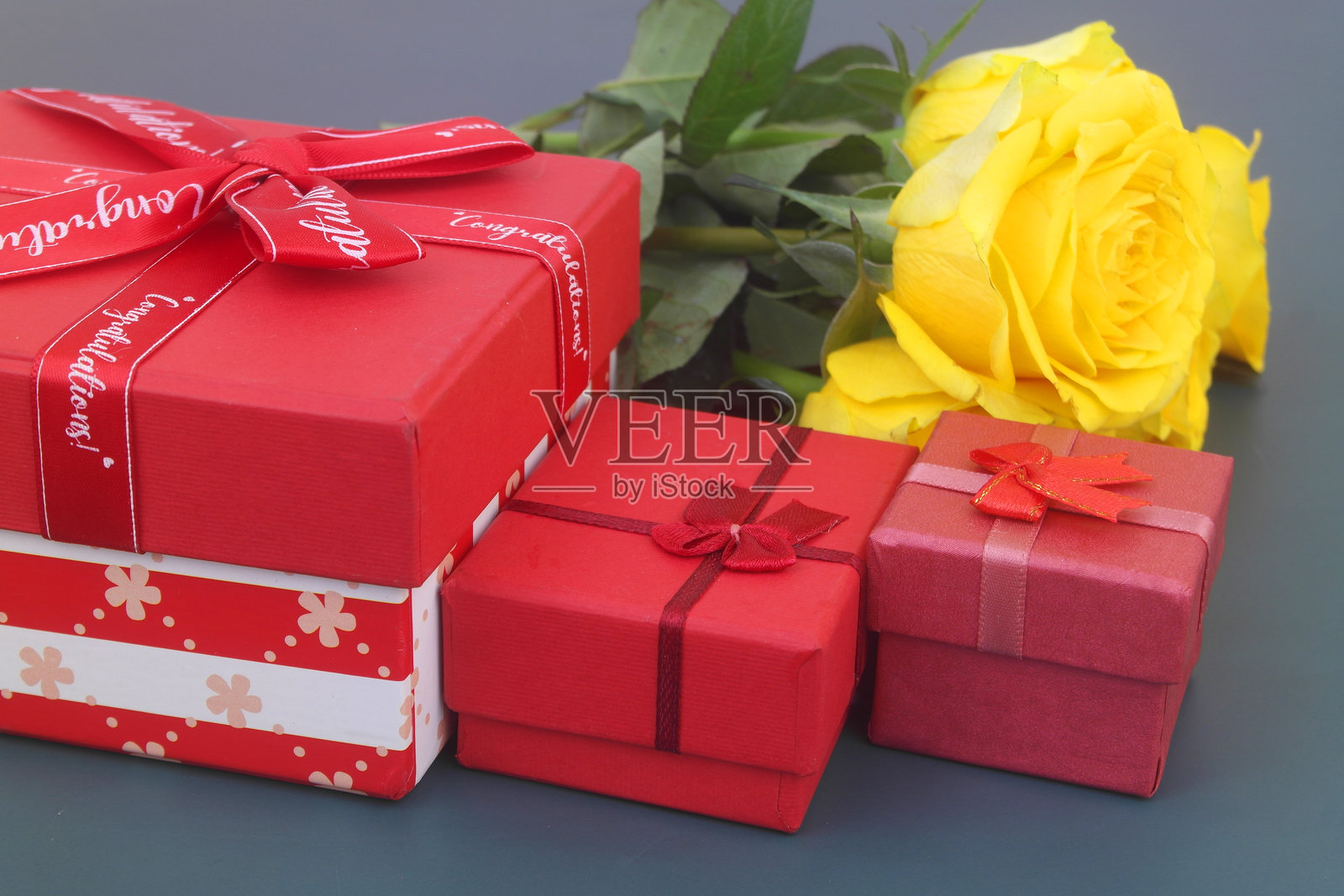 蓝色背景上的黄色玫瑰花束和礼品盒。照片摄影图片