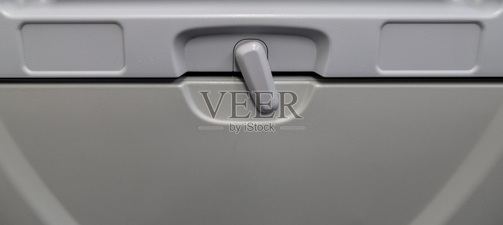 飞机经济舱座位下收起的餐桌托盘，下方是娱乐屏幕和电源插座（已关闭），特写，飞行中的餐食选择，航空旅行，休闲，商务，头等舱照片摄影图片