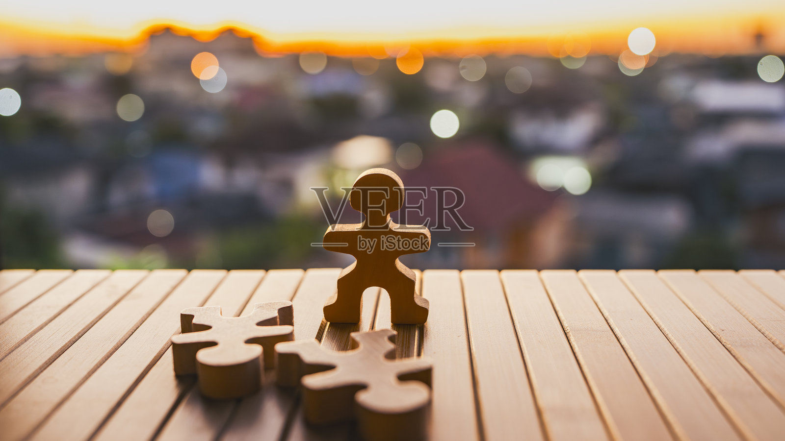 木制人偶站立，两尊倒下的模型躺在桌上，背景是城市日落，象征着商业竞争、生存、经济压力、行业颠覆以及企业为生存而挣扎。照片摄影图片