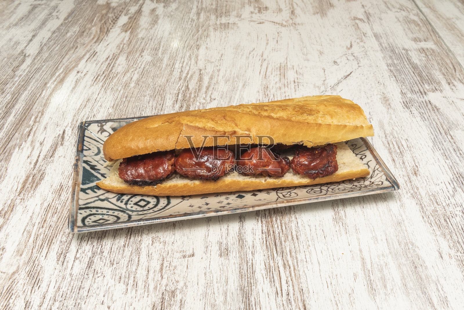 精美的西班牙炸香肠三明治，放在瓷盘和木桌上照片摄影图片
