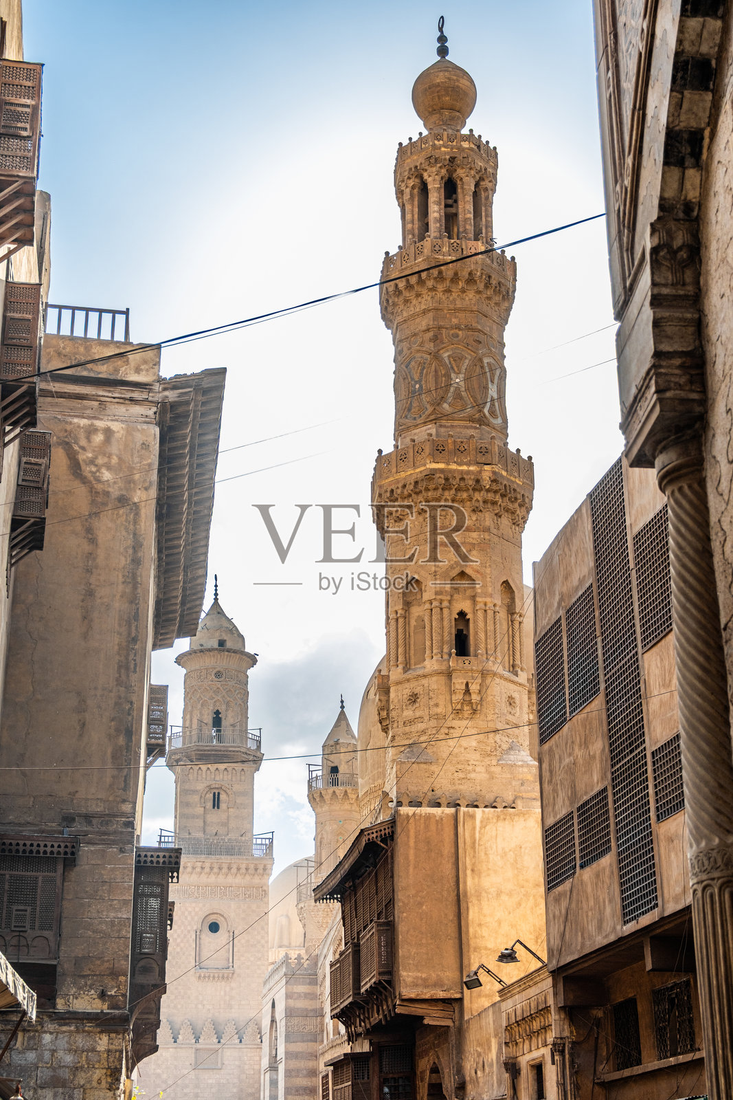 卡拉温建筑群，开罗的文化地标，拥有精美的建筑、高耸的尖塔和圆顶，在蓝天白云下，位于穆伊兹大街。照片摄影图片