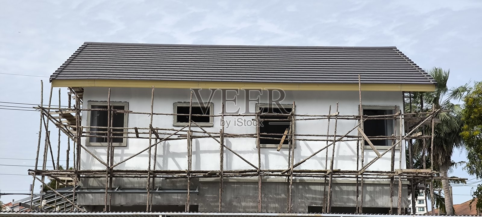 这座房屋仍在建造中，周围环绕着木制脚手架。照片摄影图片