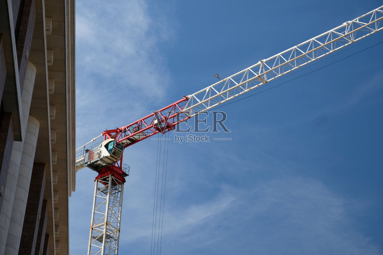 在晴朗的蓝天下，城市区域的建筑工地旁，起重机正在作业。照片摄影图片