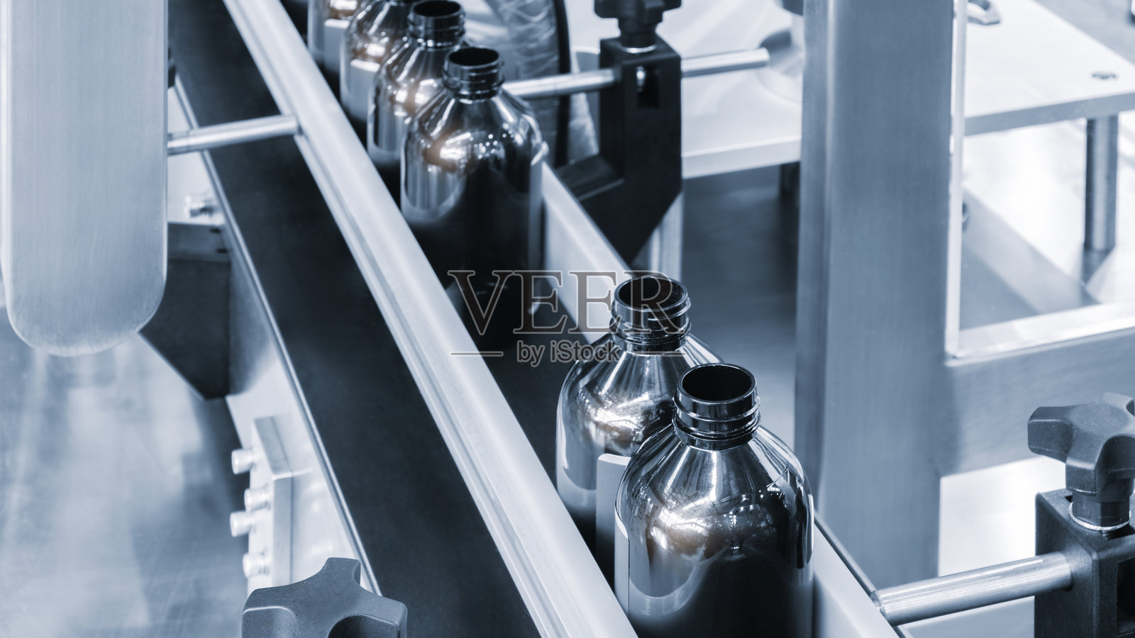 传送带上放着一排排颜色相同的瓶子。照片摄影图片