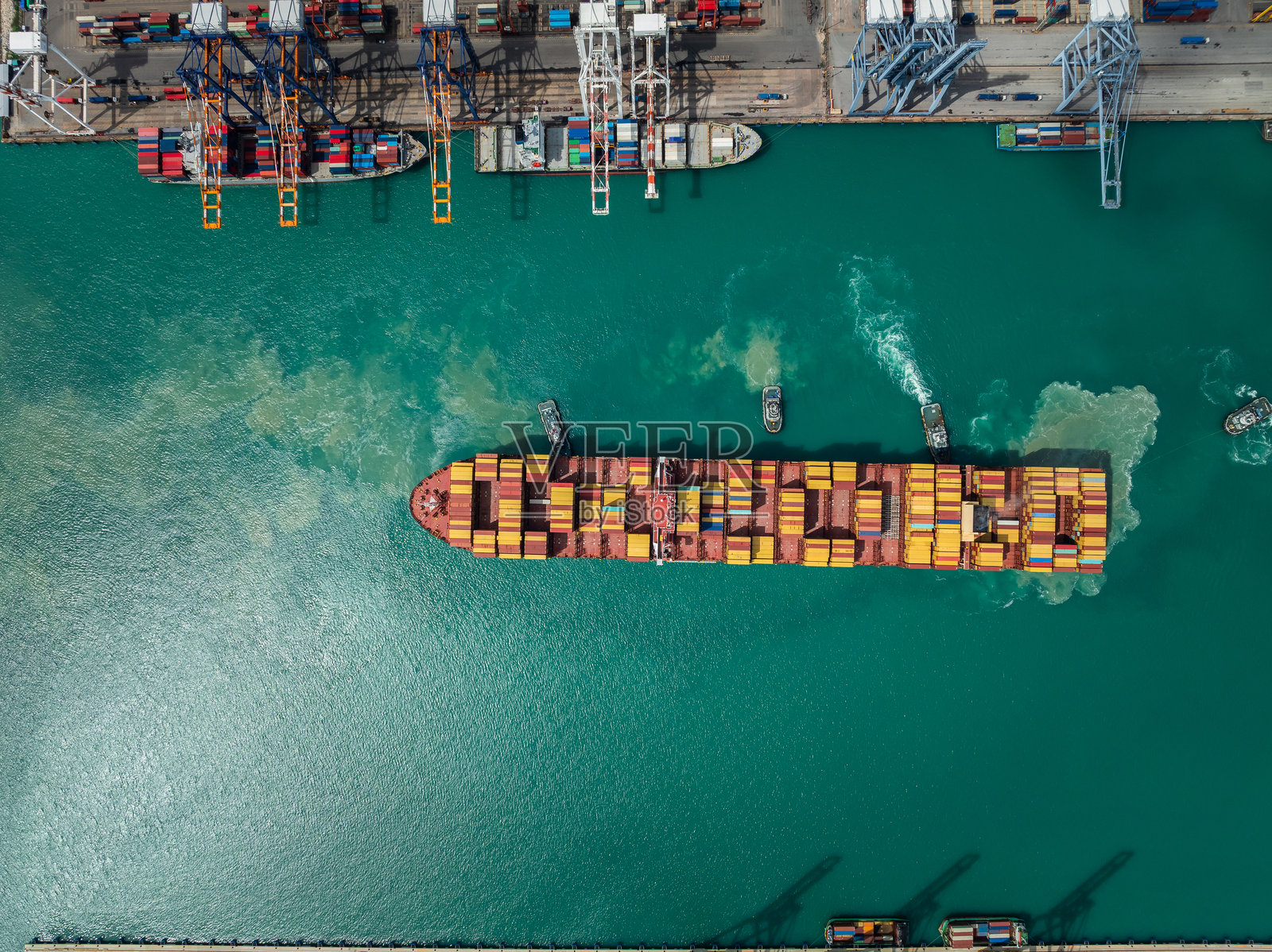 集装箱船停靠在码头，起重机正在装载货物，展现国际进出口的商业物流与运输业的航拍俯视图。照片摄影图片