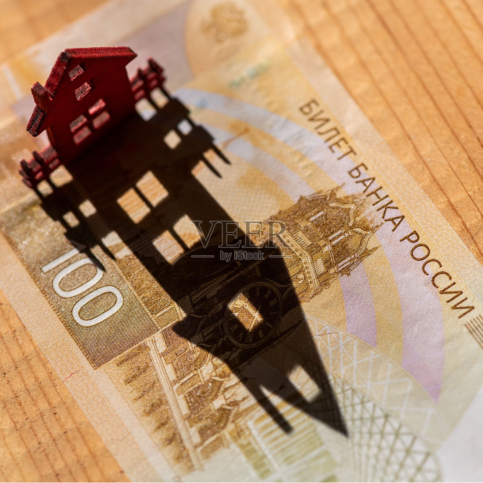 象征性的木屋在百卢布俄罗斯纸币上投下长长的阴影。照片摄影图片