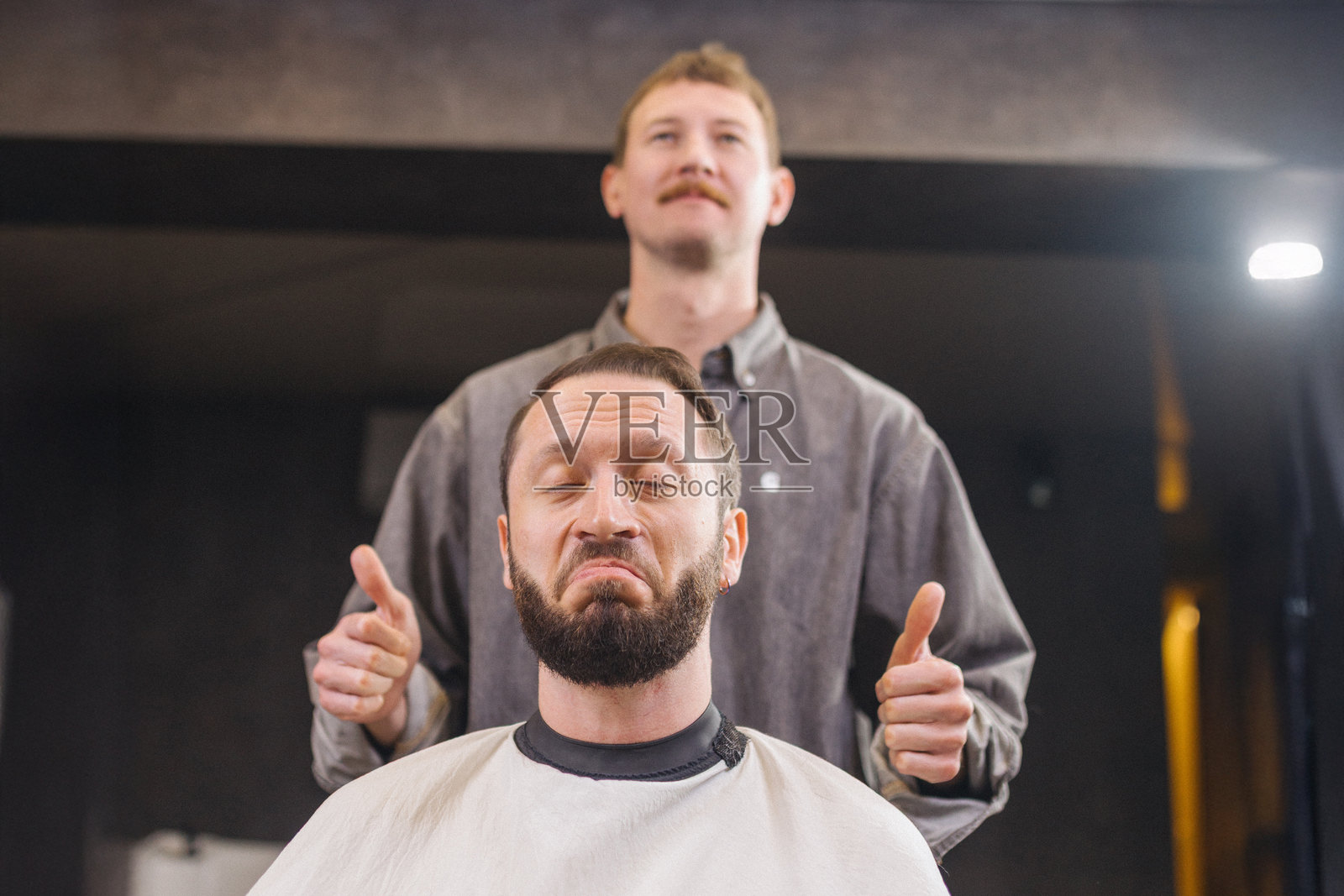 理发店里的搞笑瞬间，理发师站着照片摄影图片