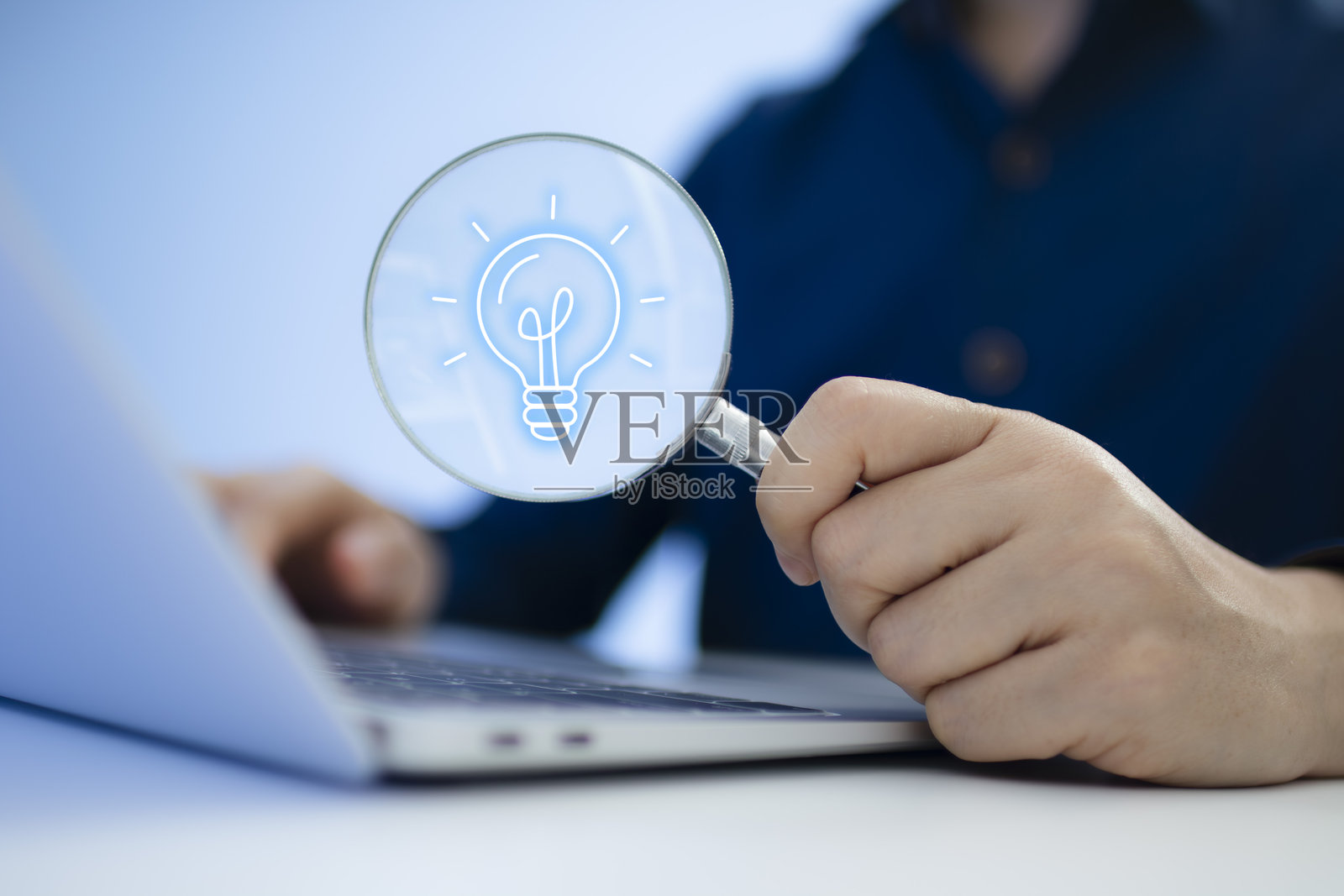 商人使用笔记本电脑，手持放大镜和灯泡图标，象征着想法和创新，以及解决问题的概念照片摄影图片