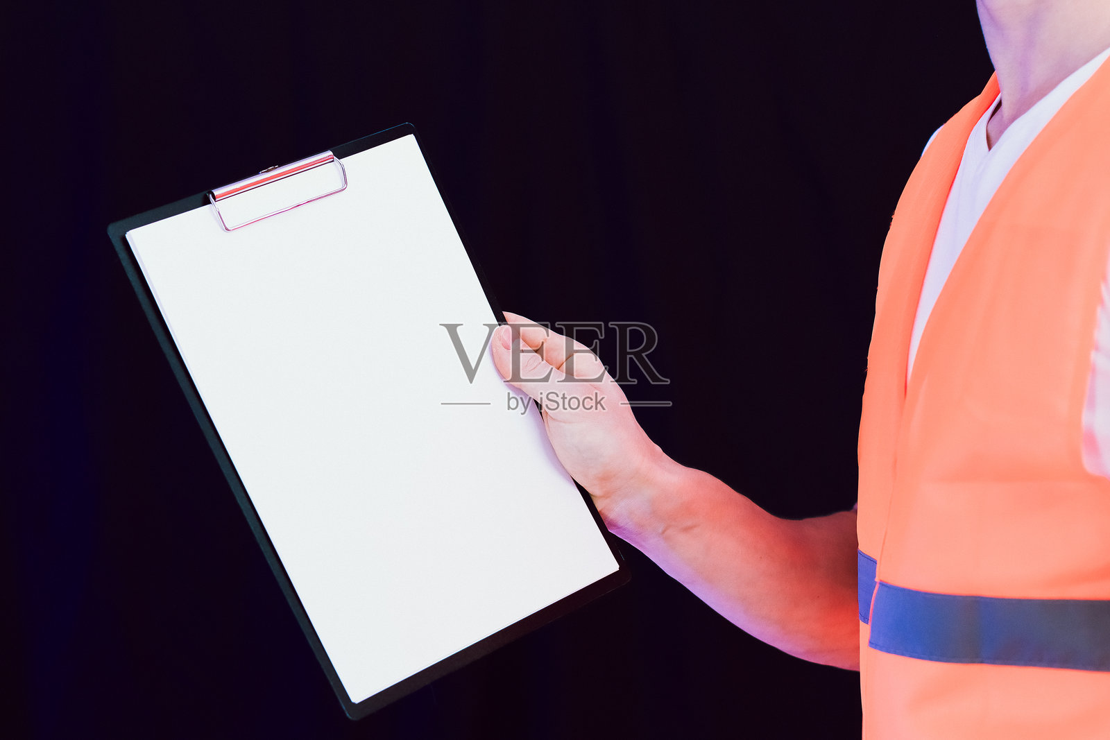 一只穿着橙色安全背心的手垂直伸出一块空白的剪贴板照片摄影图片