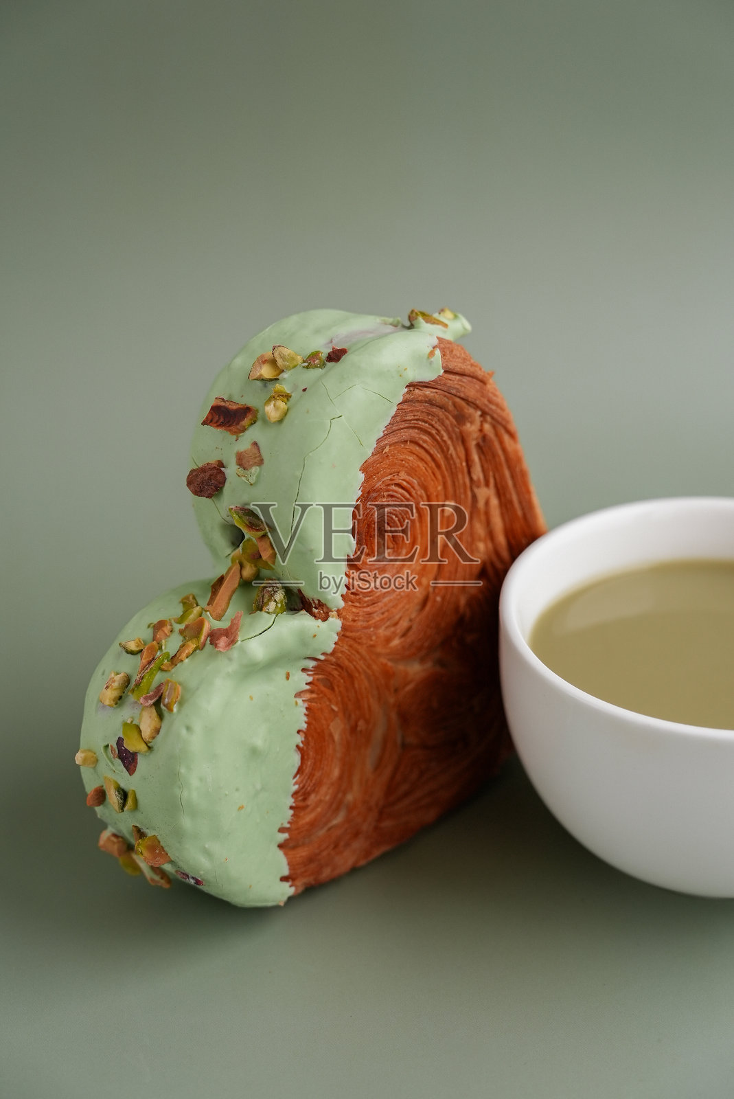 营养丰富的抹茶饮品，绿拿铁抹茶咖啡，搭配令人愉悦且充满活力的心形糕点牛角包，顶部装饰着五彩缤纷的糖霜和坚果。样机模板复制空间。美食实验病毒式甜点创意照片摄影图片