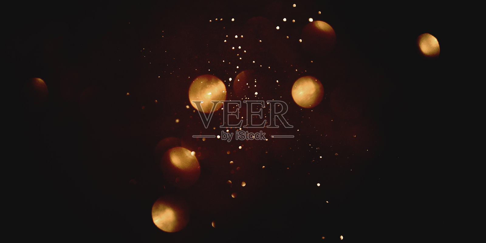 黑色背景上的金色抽象散景。照片摄影图片