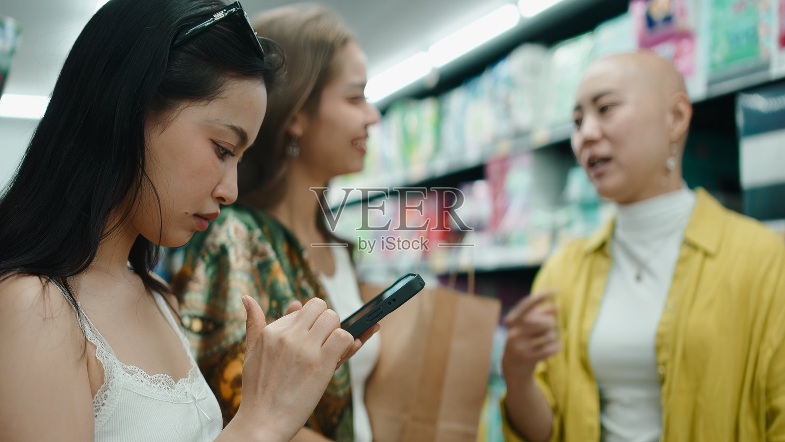 亚洲朋友们在曼谷的商店里购买杂货，一边看手机一边聊天照片摄影图片