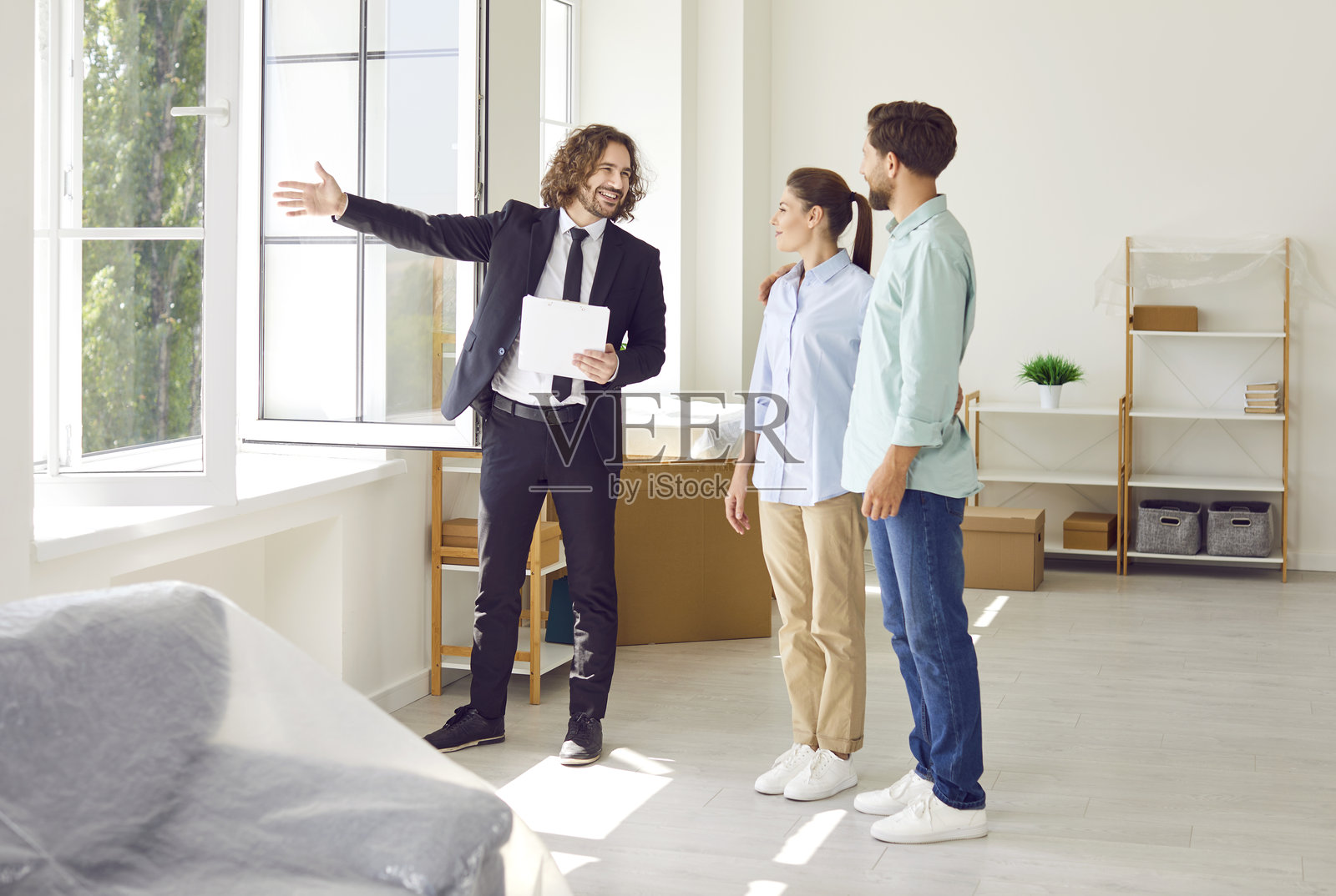 房地产经纪人向一对年轻快乐的夫妇展示房屋。房地产市场概念。照片摄影图片