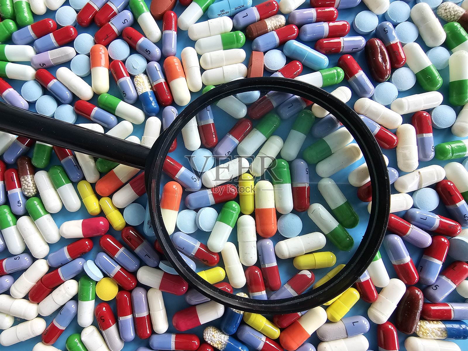 放大镜下的各种药丸和胶囊特写照片摄影图片