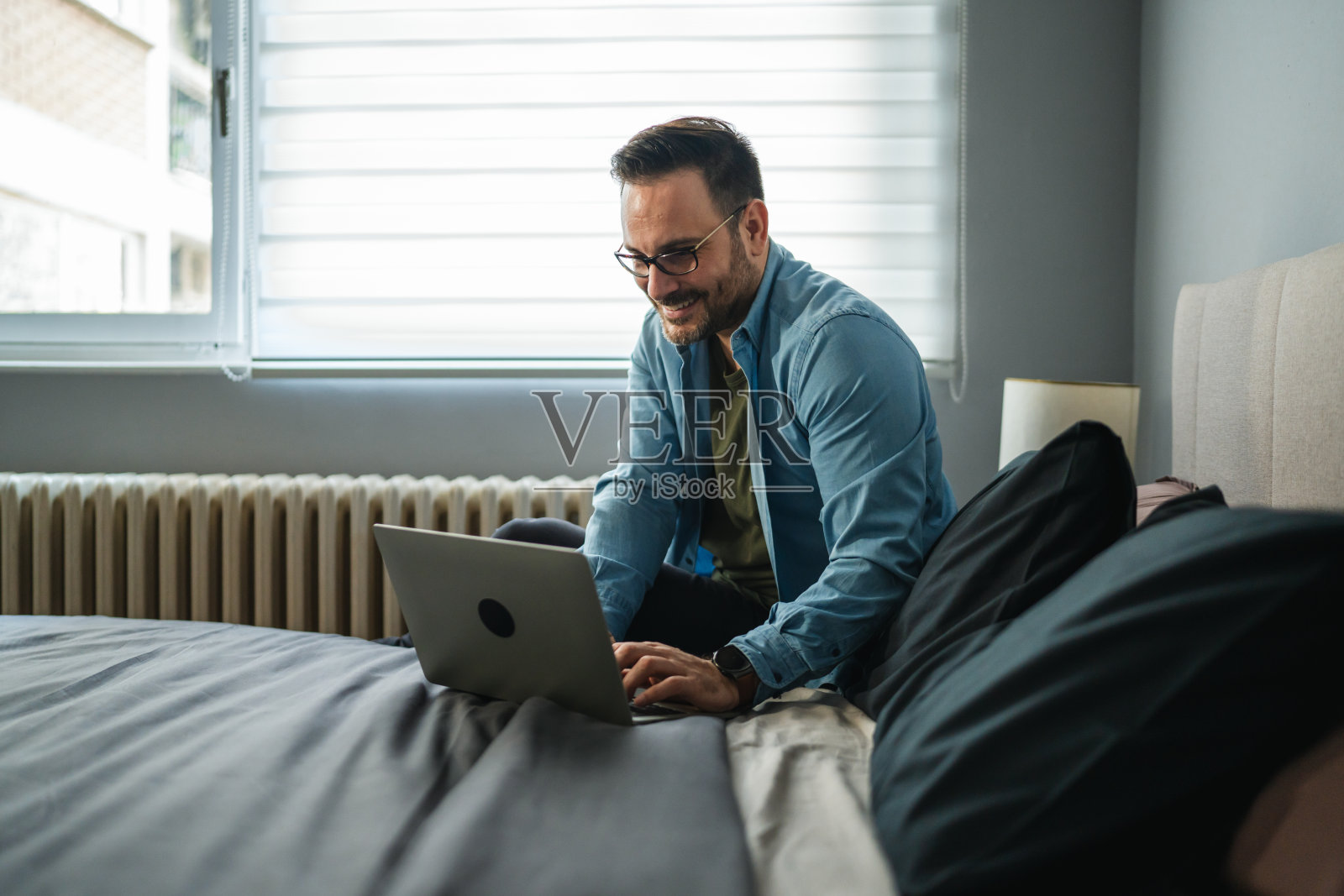 在家床上用笔记本电脑工作的男人照片摄影图片