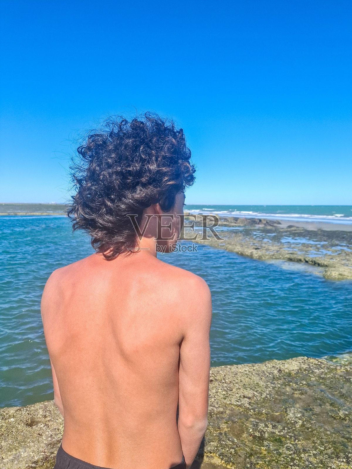 在巴塔哥尼亚大西洋海边，一名青少年在潮汐池中眺望地平线照片摄影图片