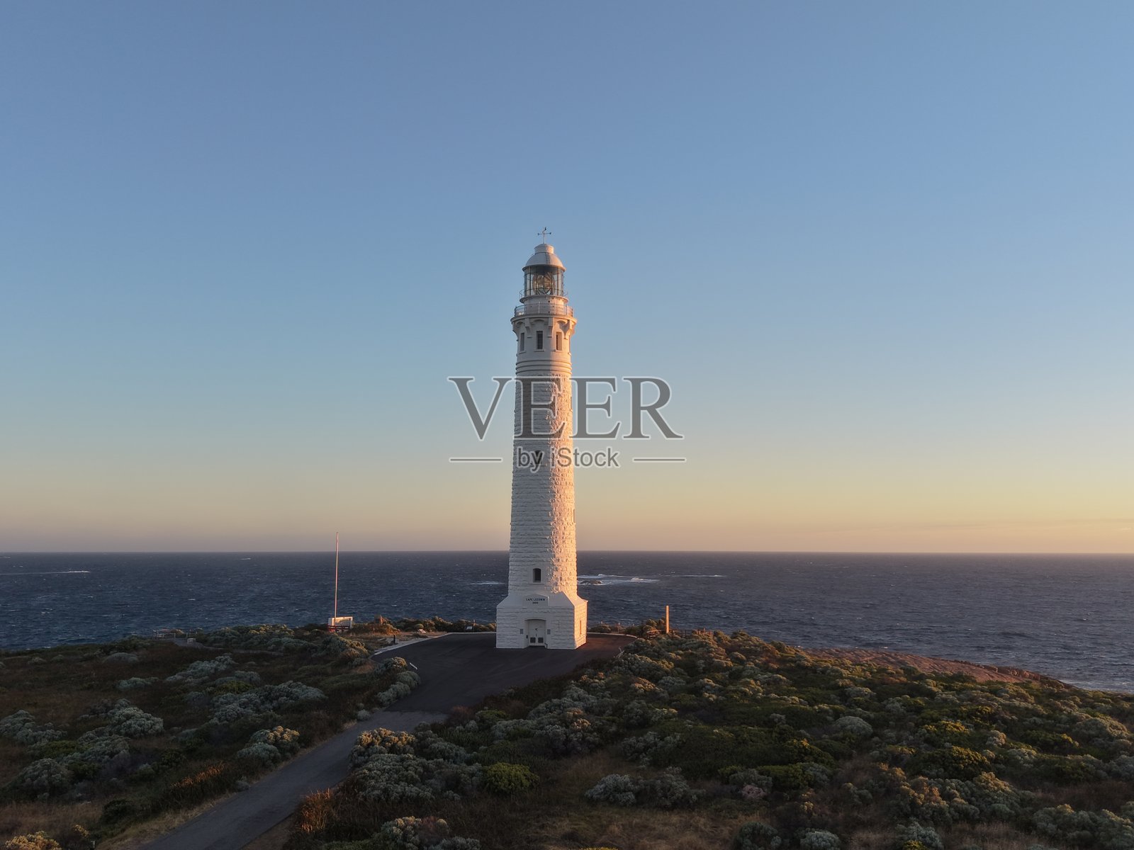 澳大利亚大陆最高灯塔——鲁文角灯塔，坐落于崎岖海岸线上，日落时分，地平线横跨南印度洋，呈现全景照片摄影图片