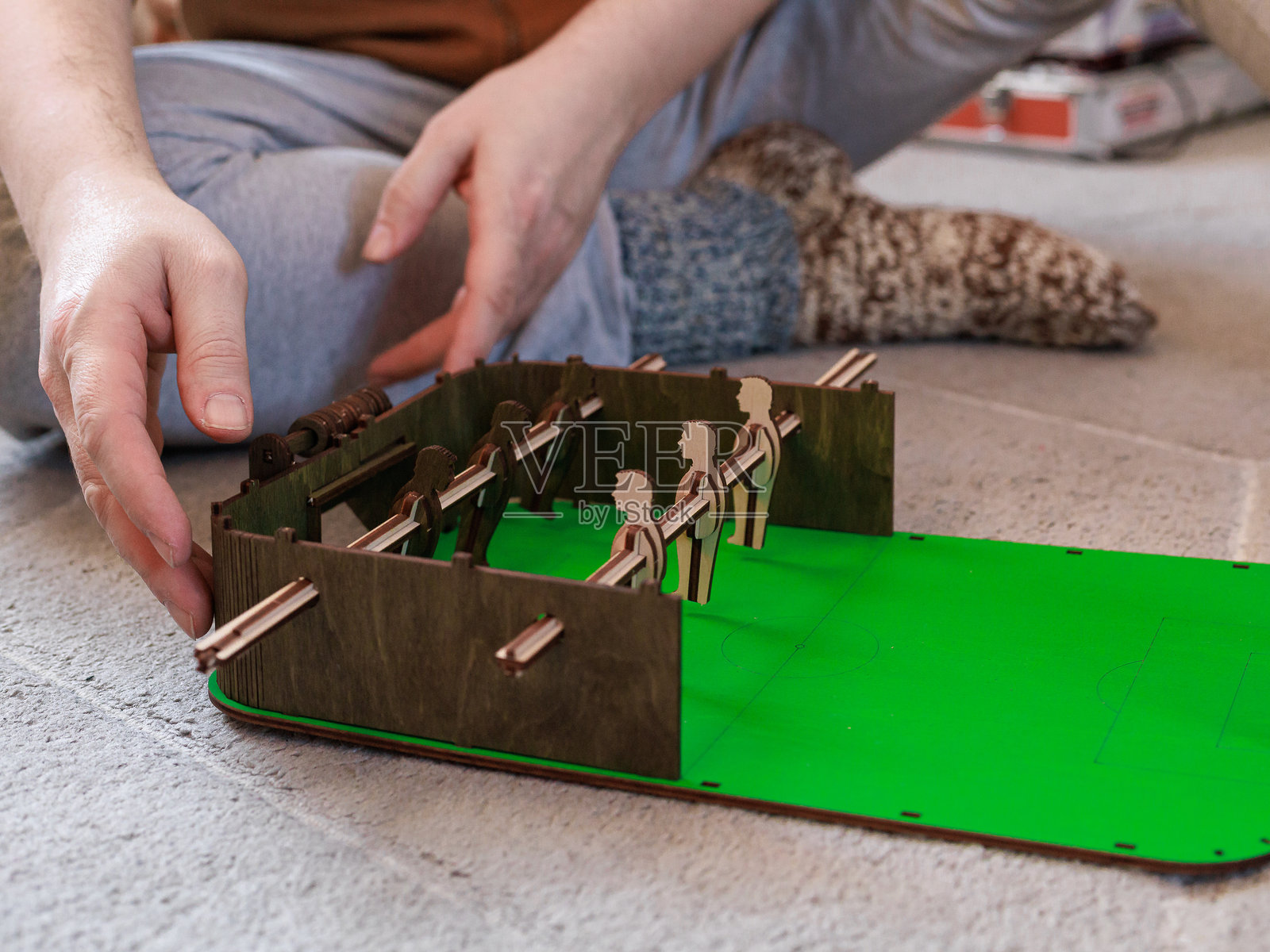 一名成年男子在家中组装复古桌上足球游戏，连接木制部件。体现了分步建造、怀旧爱好和专注休闲的概念。照片摄影图片