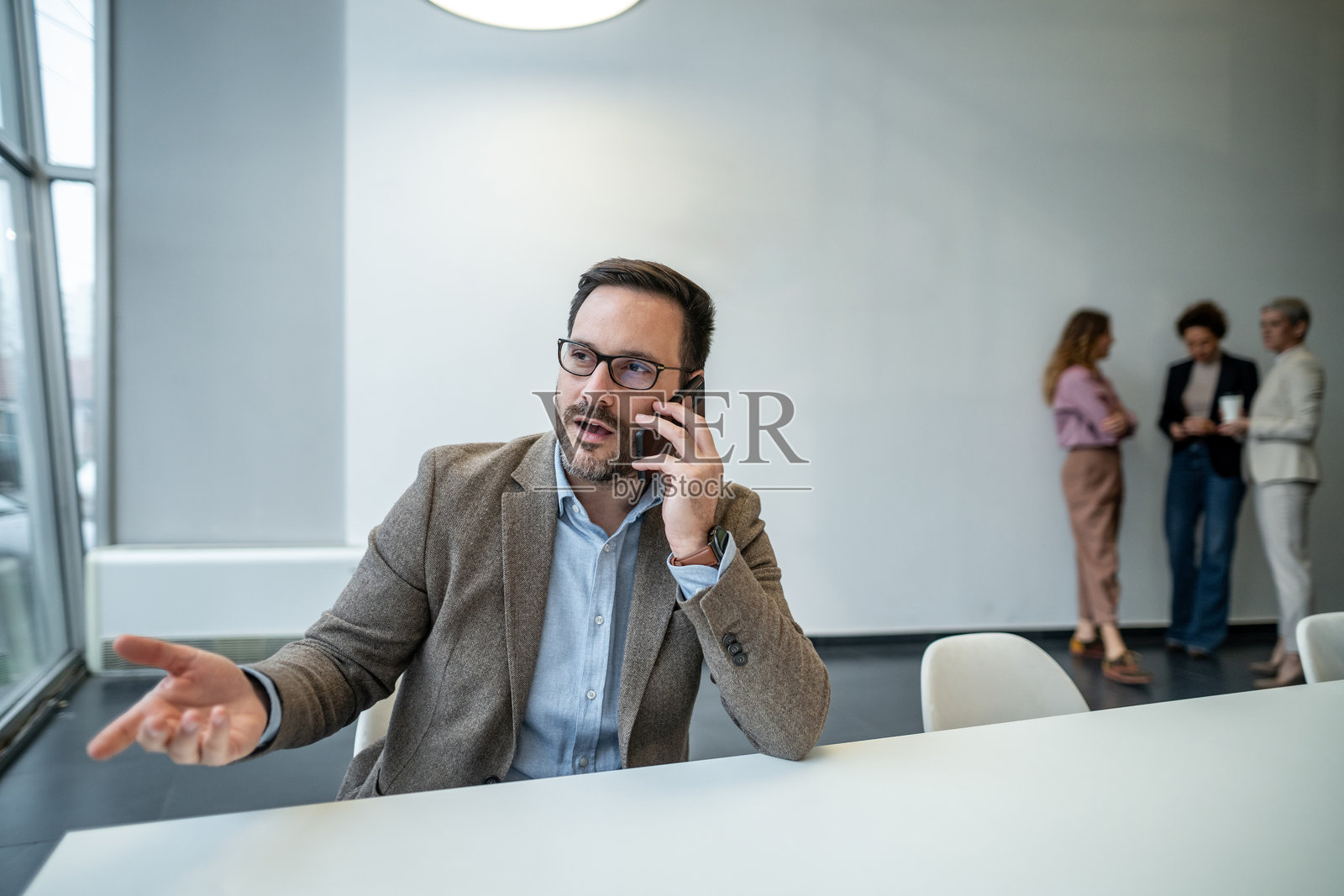 商务人士在办公桌前用手机通话照片摄影图片