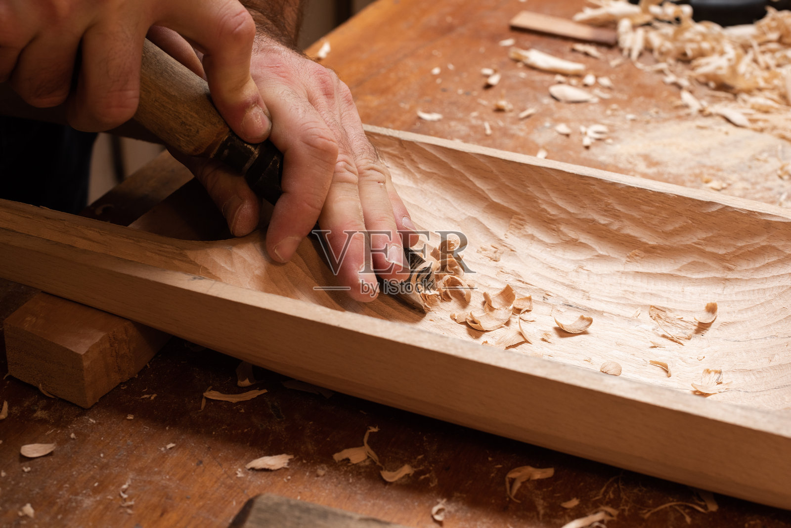 师傅用一块木头雕刻出塔格哈克，凿子工艺照片摄影图片