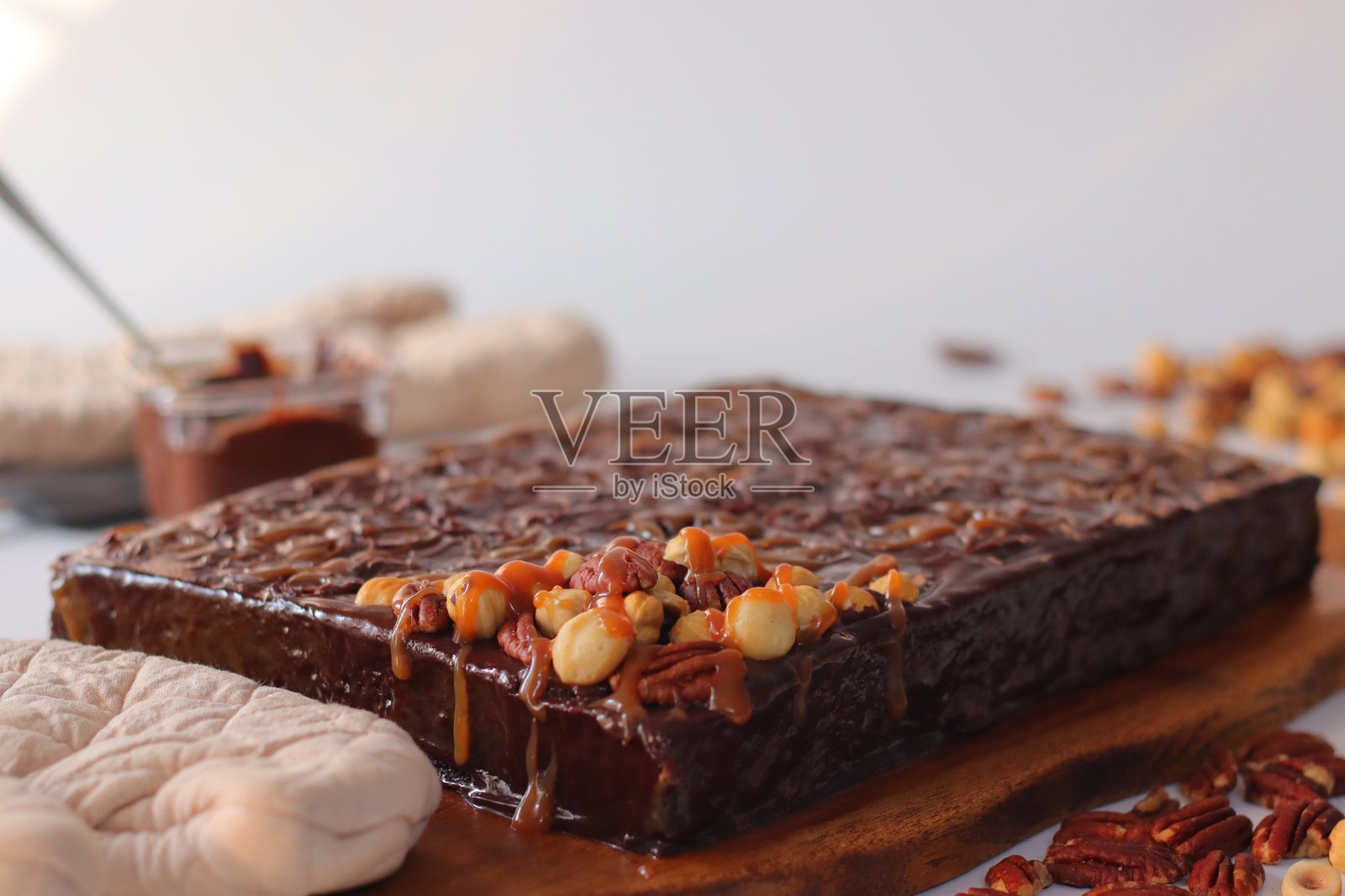 木板上盛着的巧克力焦糖蛋糕，淋有焦糖酱并撒有坚果碎照片摄影图片