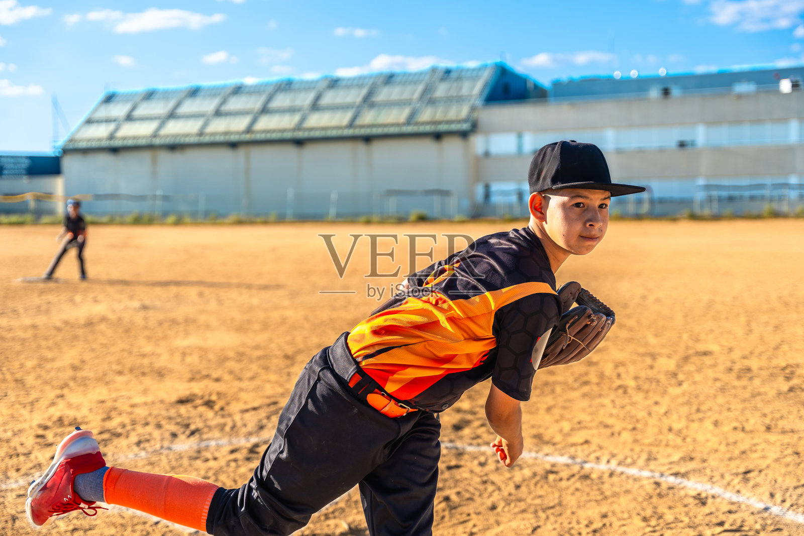 年轻的棒球投手在尘土飞扬的球场上投球照片摄影图片