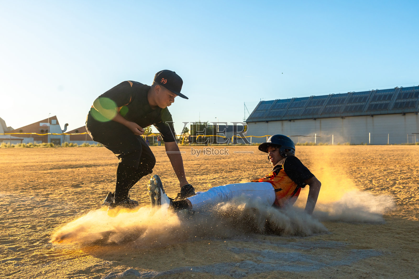 年轻的棒球运动员滑垒，激起尘土照片摄影图片