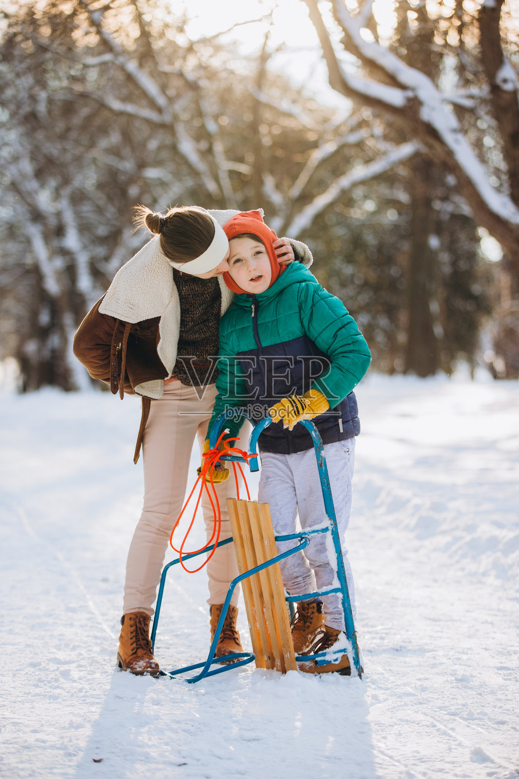 妈妈在冬天的公园里深情地抱着儿子照片摄影图片