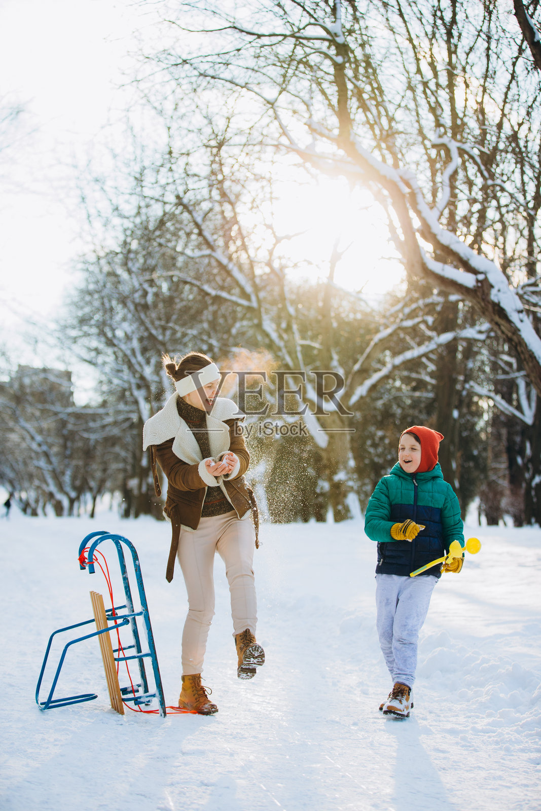 母子在冬日公园里享受嬉戏的雪天照片摄影图片