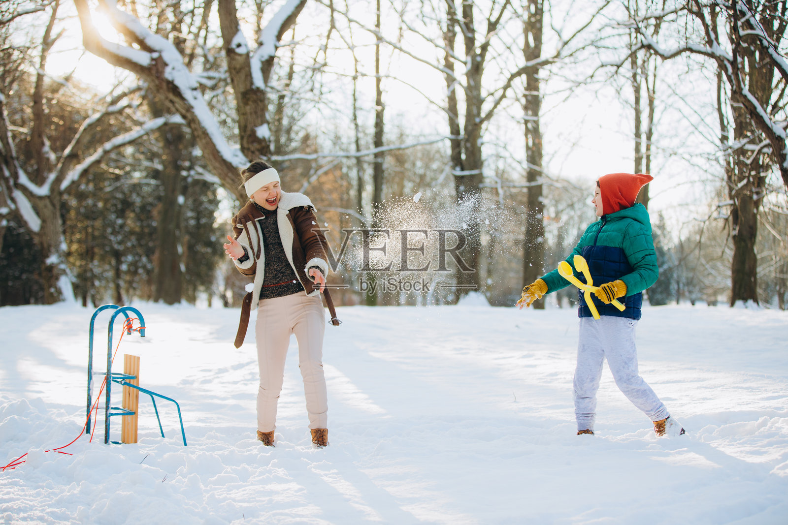 母子俩在冬日里嬉戏打雪仗照片摄影图片