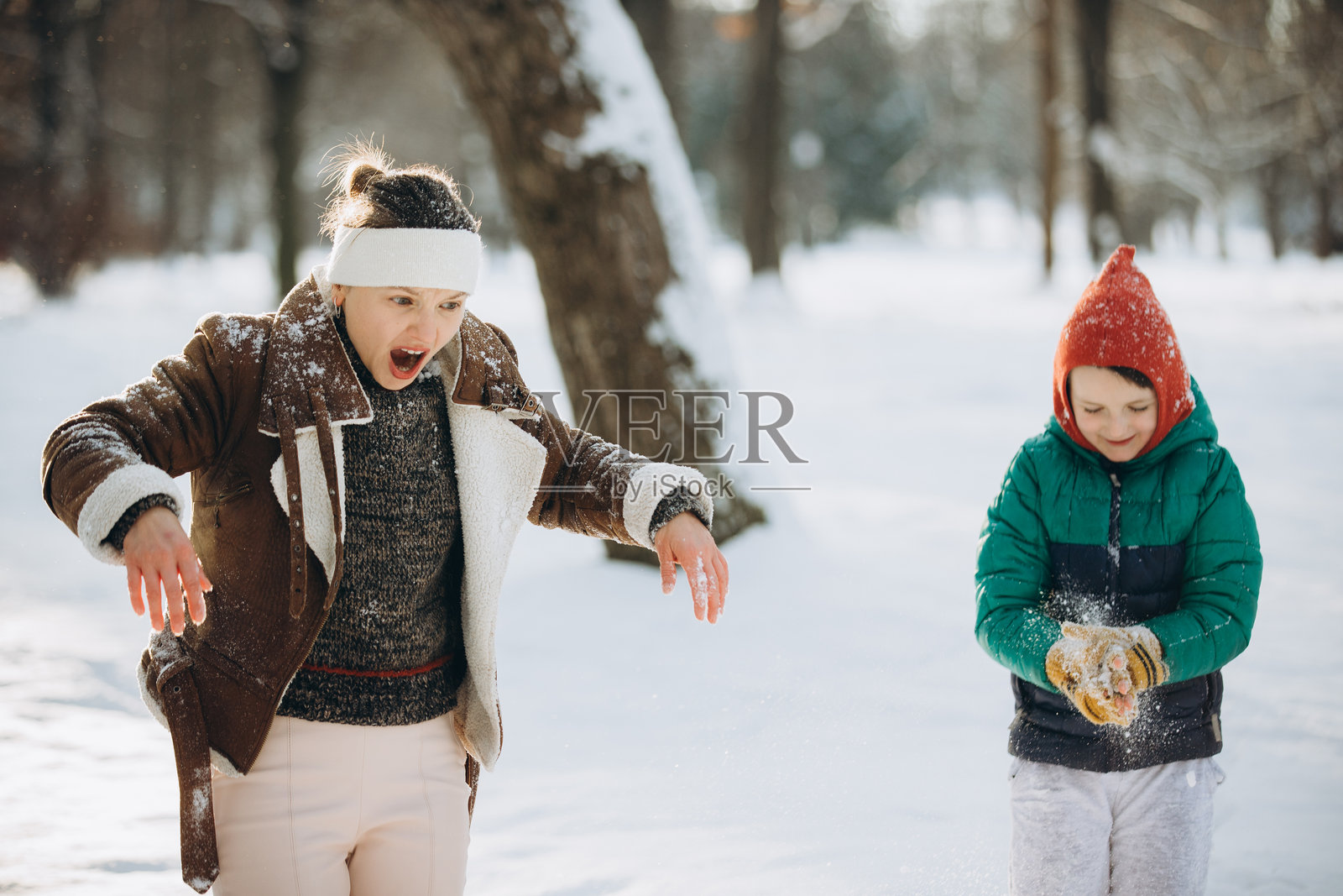 冬天公园里，母亲对儿子扔雪的反应照片摄影图片