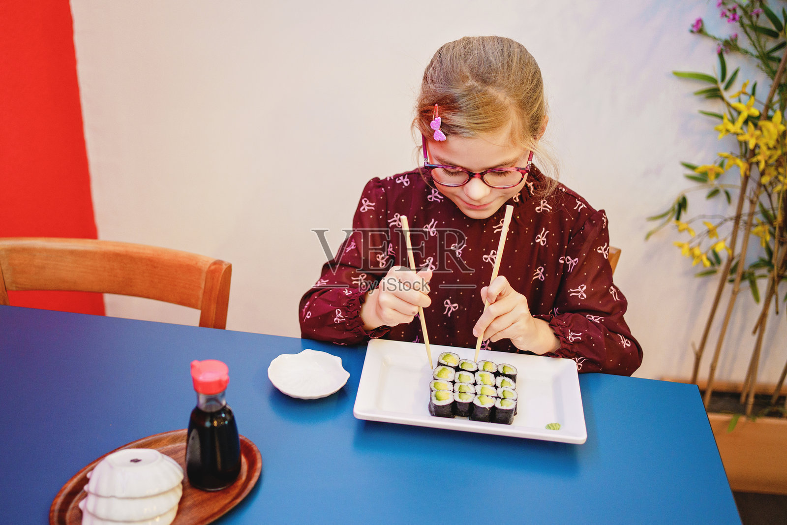 小女孩在餐厅里吃寿司。快乐的孩子，健康的食物。照片摄影图片