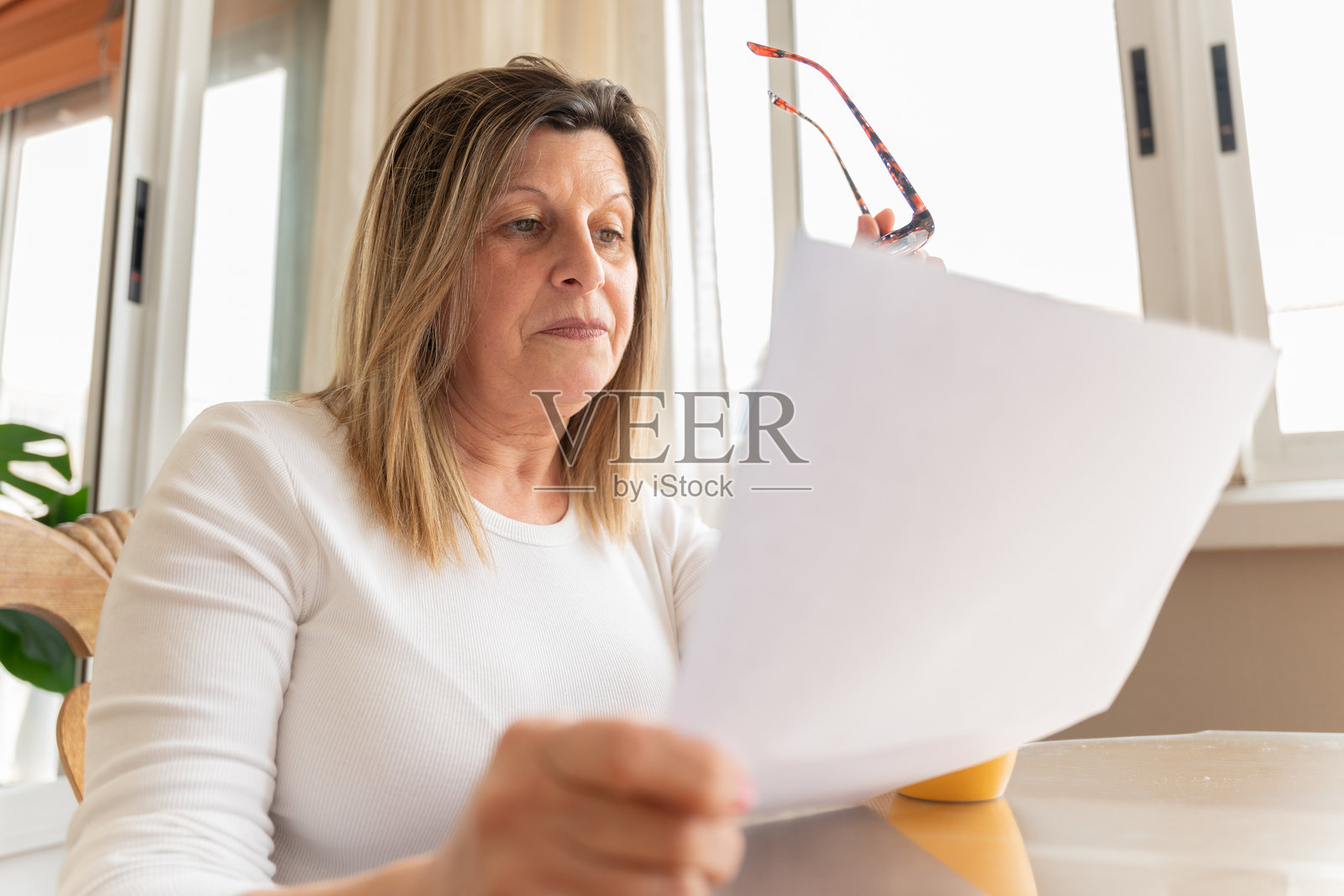 一位成熟的成年女性在家中阅读重要的文件照片摄影图片