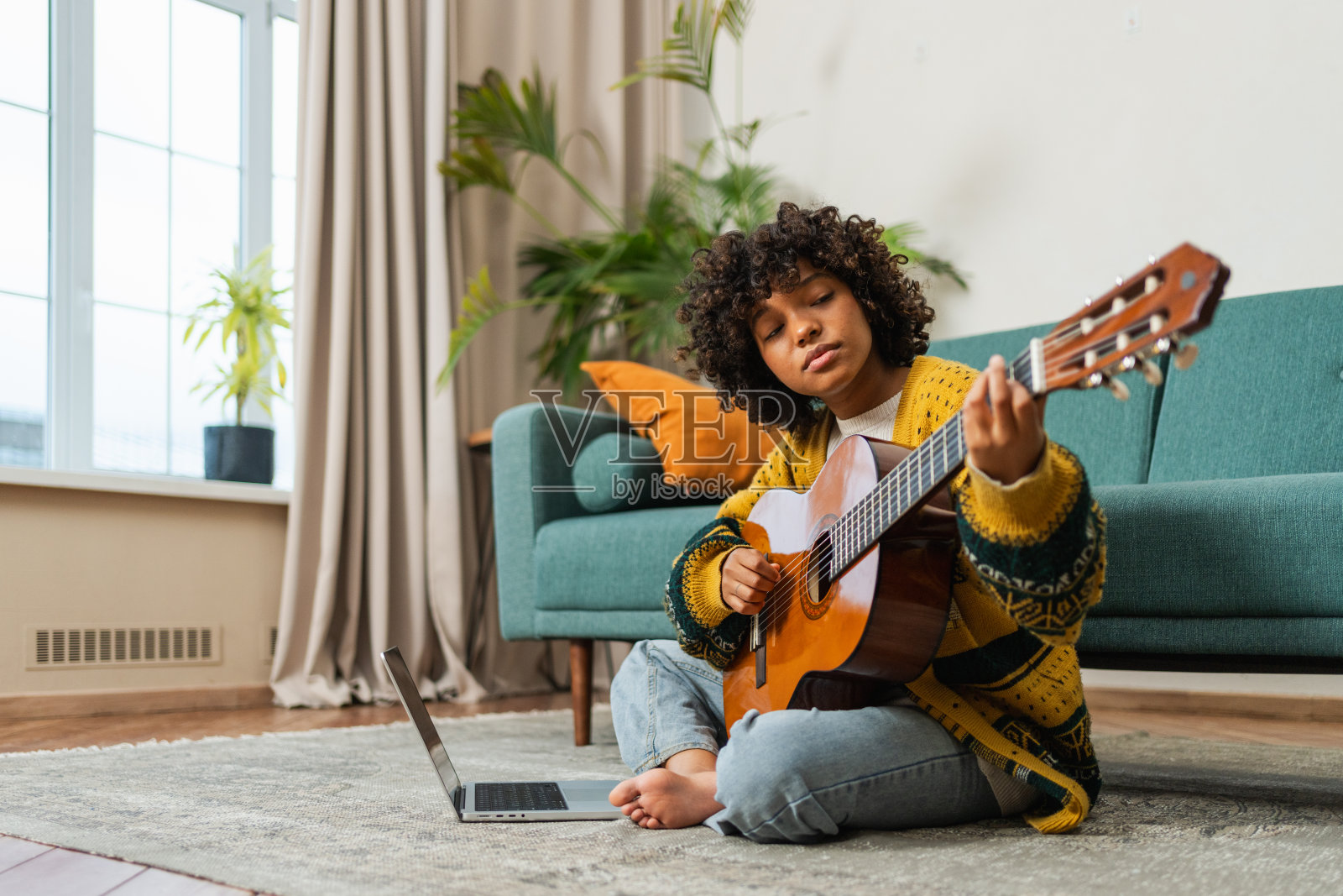 博主吉他手。快乐的非裔美国女孩博主弹吉他唱歌，录制视频博客。社交媒体影响者女性在家工作室直播录制。音乐内容创作者广播。照片摄影图片