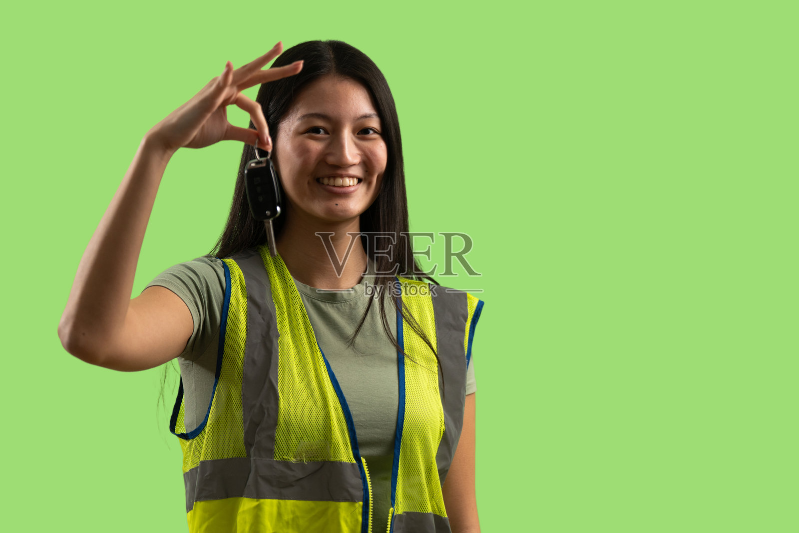 年轻的女工作人员身穿反光背心，手持车钥匙照片摄影图片
