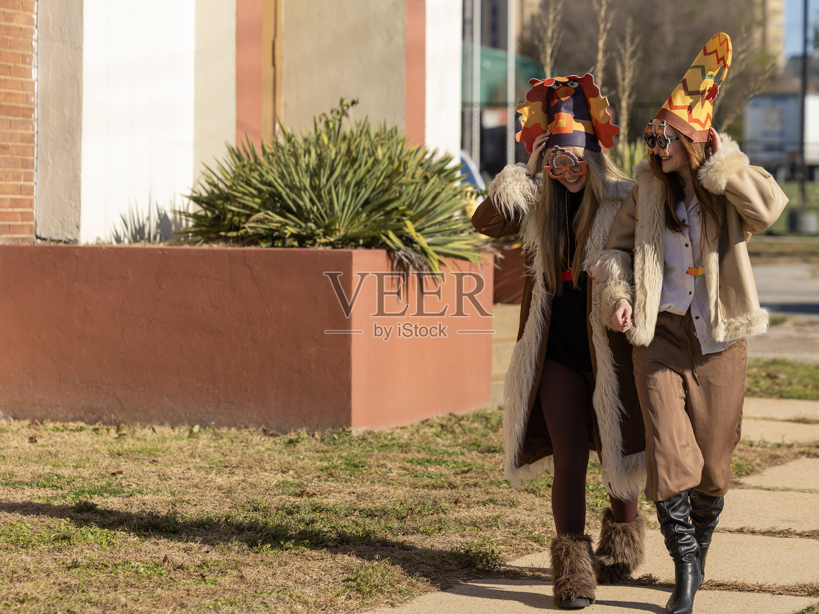 两位开心地笑着的女士戴着火鸡帽子和眼镜，庆祝感恩节。照片摄影图片