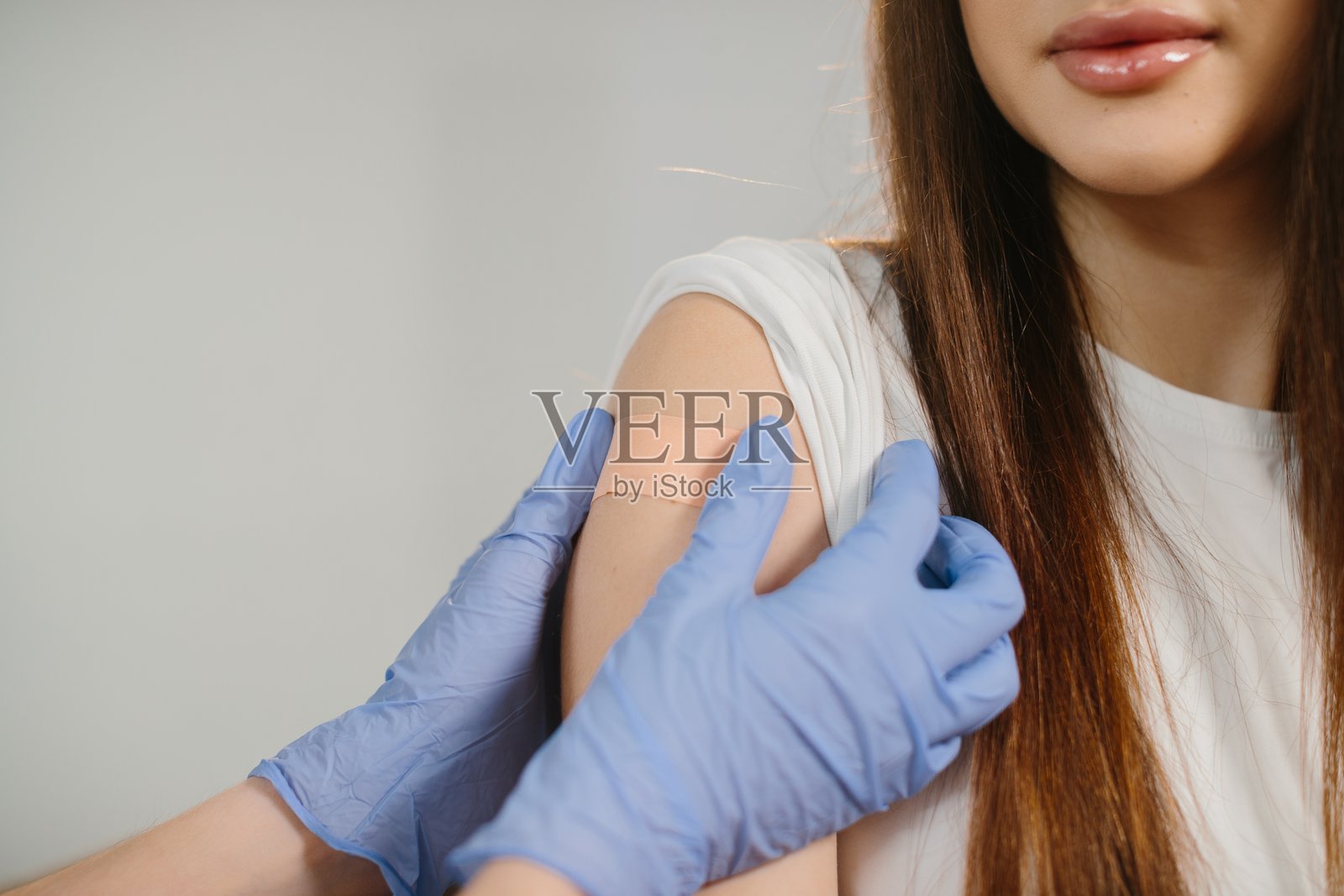 一个人正在接种疫苗，医务人员正在贴上创可贴照片摄影图片