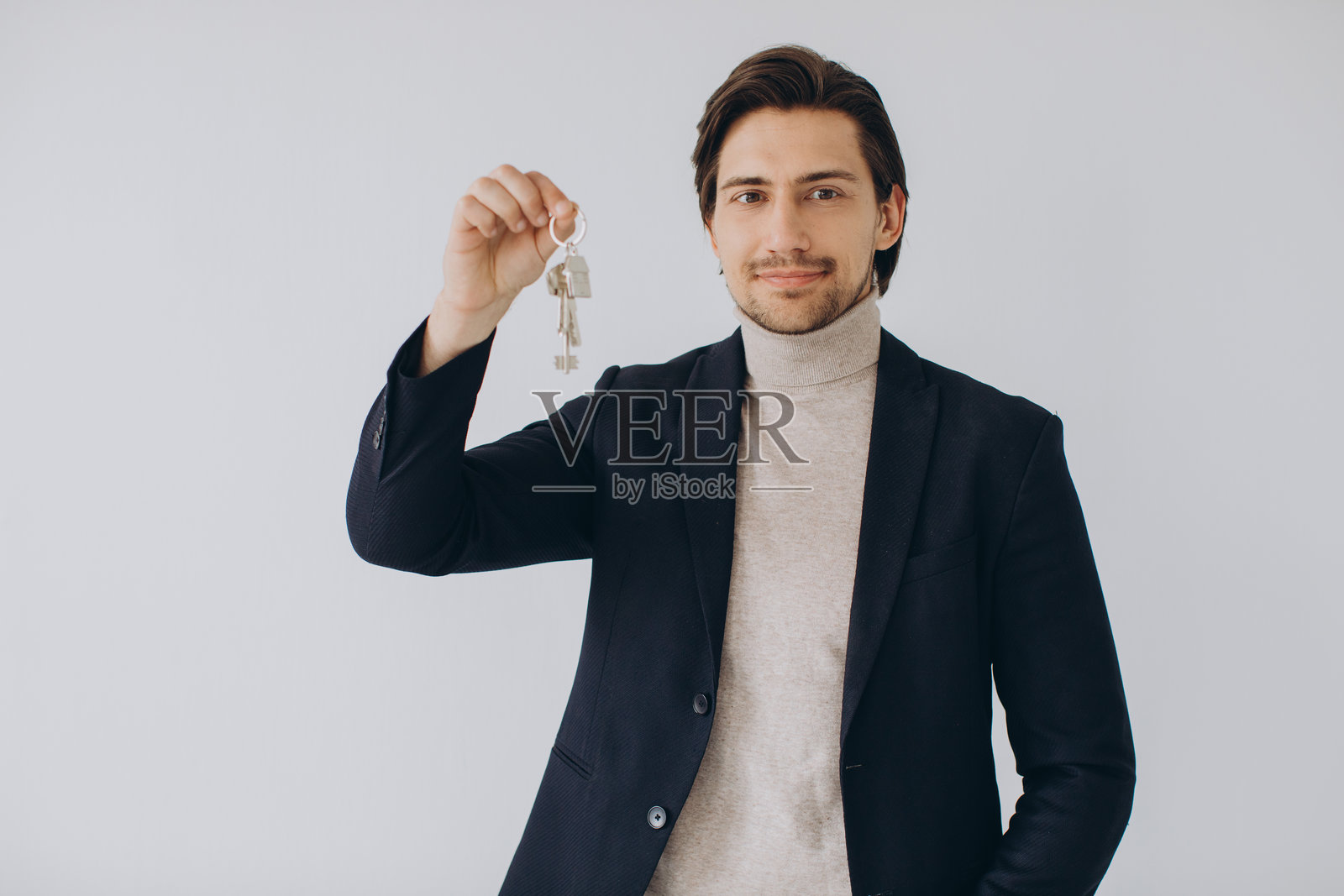 男性房产经纪人手持钥匙，象征着新家所有权和房地产投资照片摄影图片