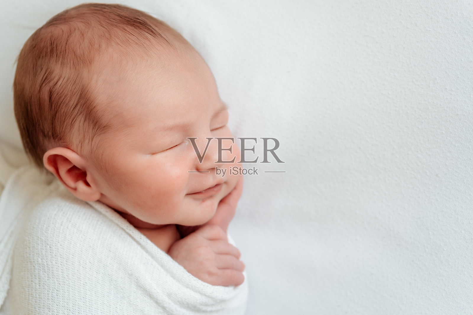 家里，新生儿睡在白色床上，包裹在襁褓中的新生儿，可供文字放置的空间照片摄影图片