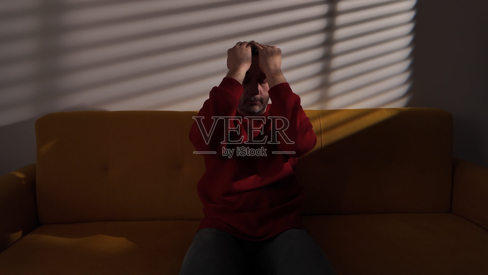 男人在家坐在沙发上，感到头痛、沮丧、悲伤和孤独照片摄影图片