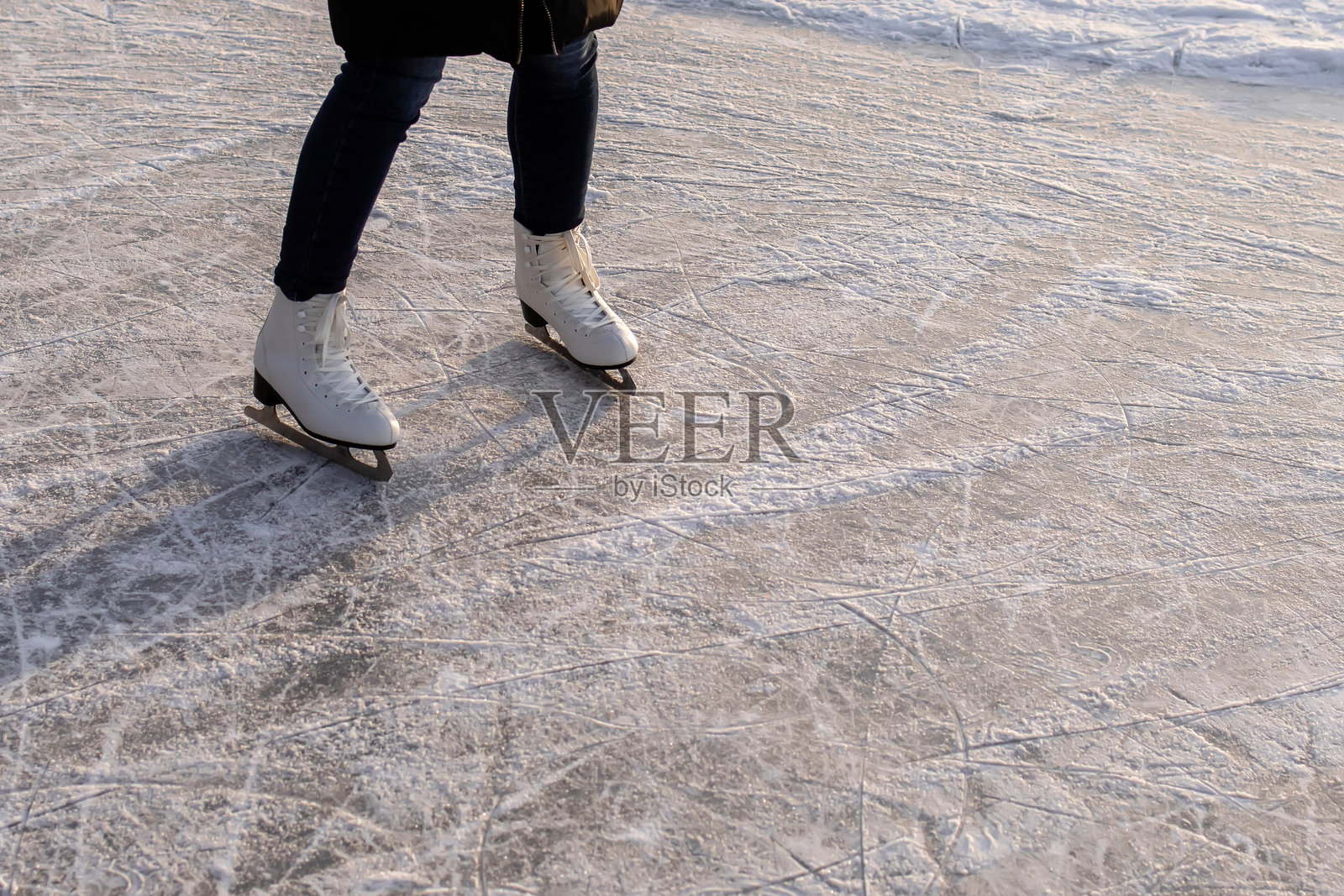 特写：冰场上带有冰刀划痕和图案的白色花样滑冰鞋照片摄影图片