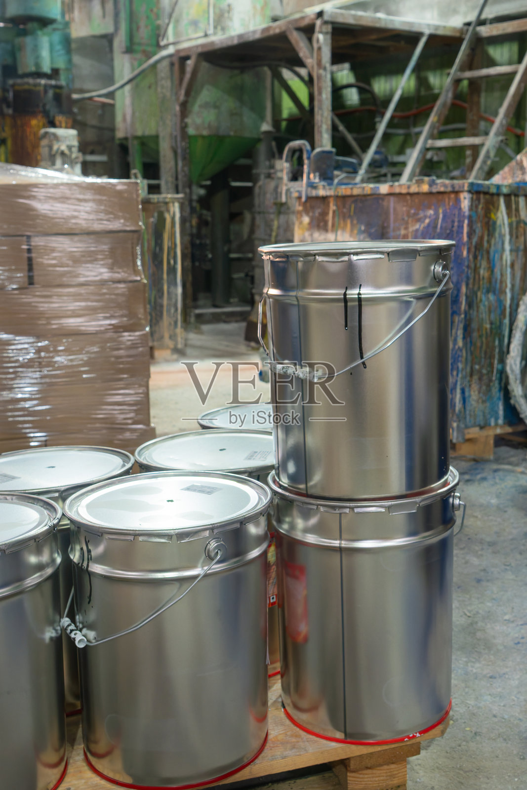 化工厂的化学品储存区，有近期使用痕迹和后勤准备。生产设施内部有密封的油漆桶和堆叠的箱子照片摄影图片