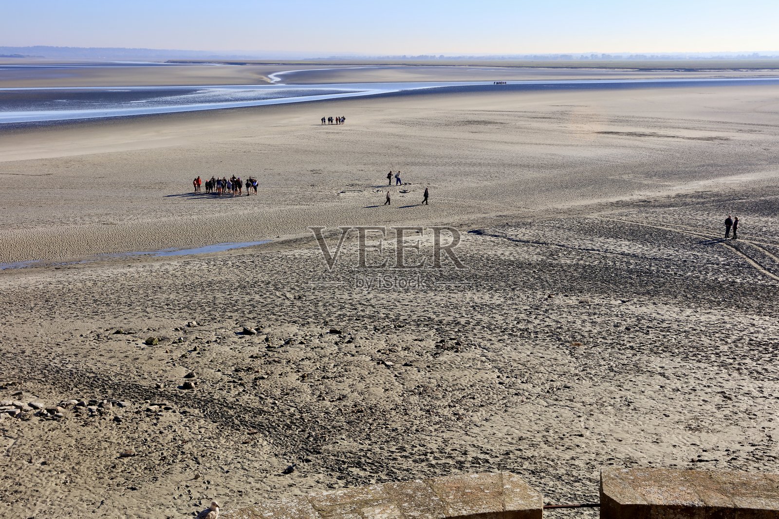 退潮时，人们在诺曼底海岸蒙圣米歇尔外的海滩上行走照片摄影图片