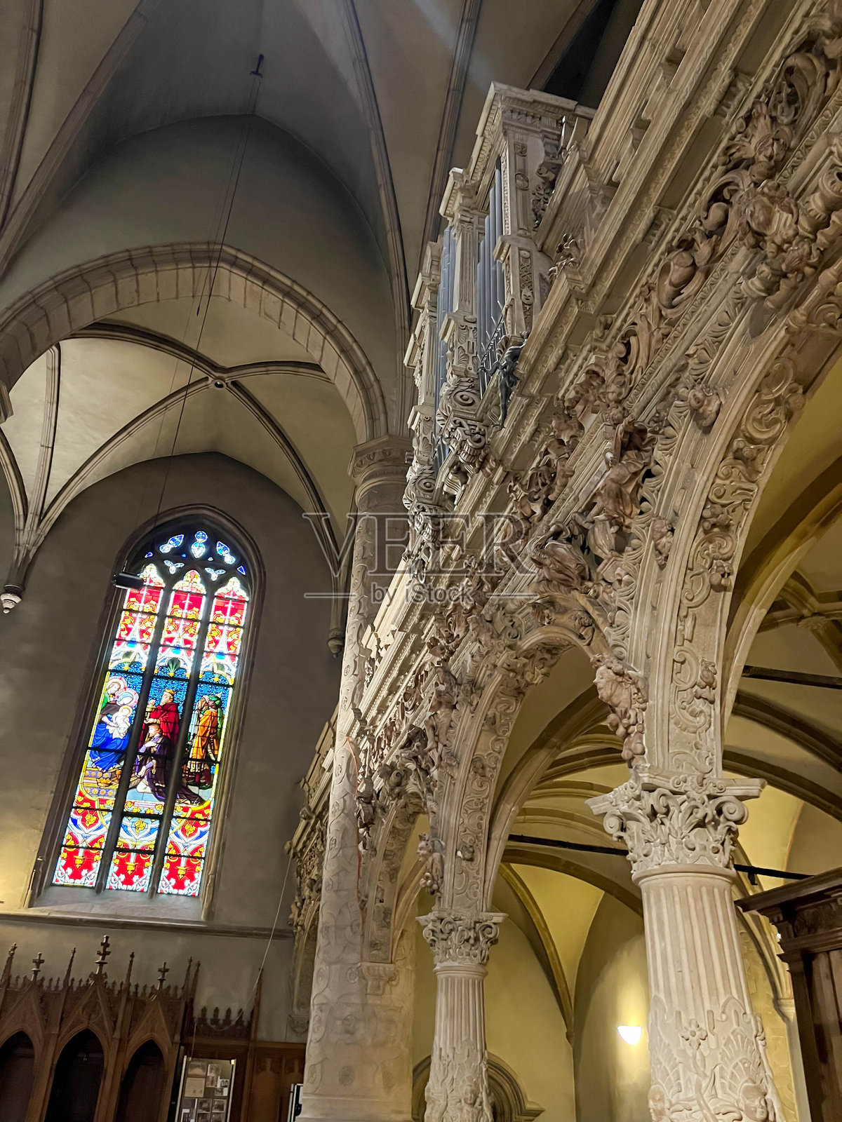哥特式彩绘玻璃窗背景下，支撑管风琴的夹层石雕柱细节。卢森堡大教堂。照片摄影图片