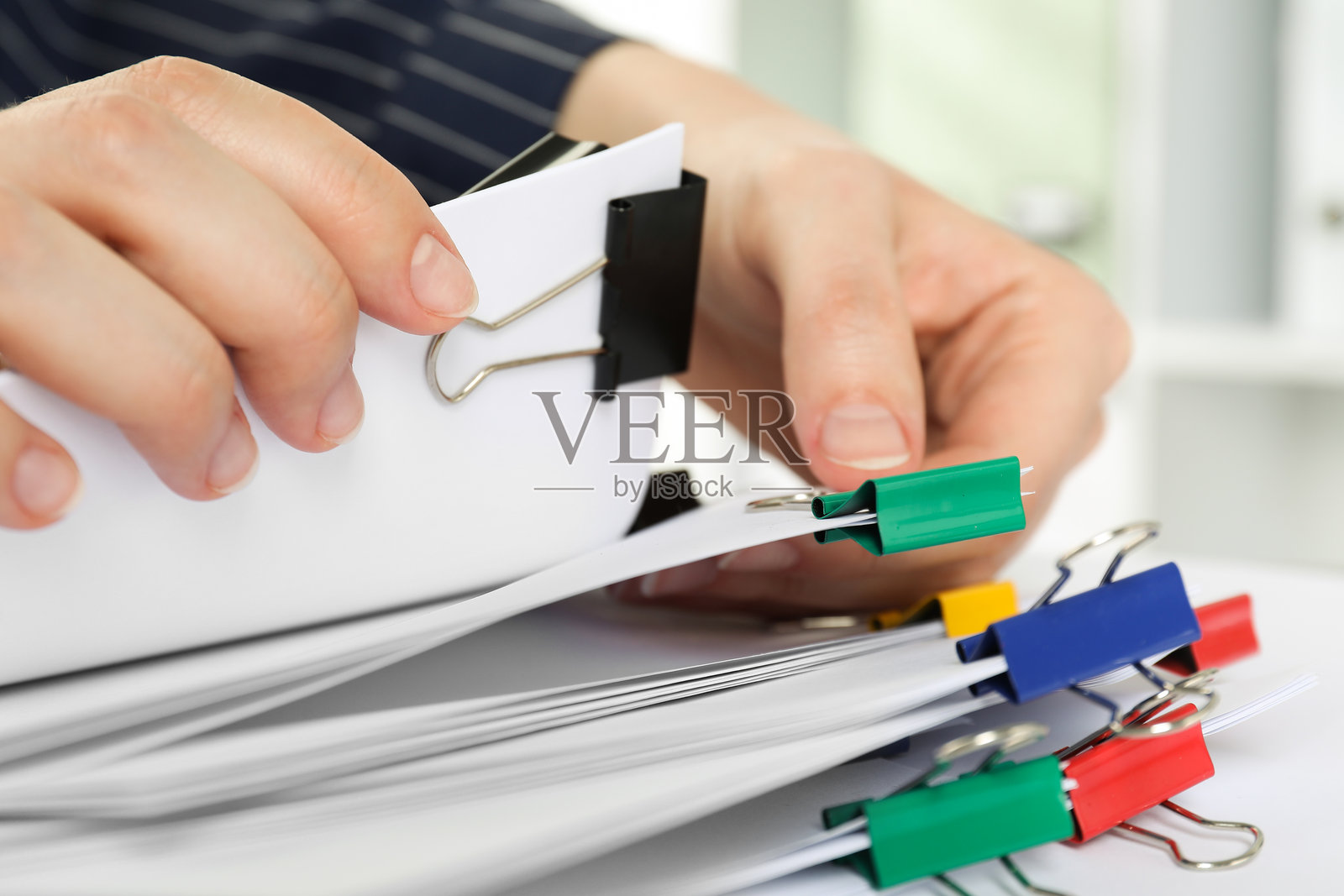 特写：女子在桌上拿着带有金属夹子的纸张照片摄影图片