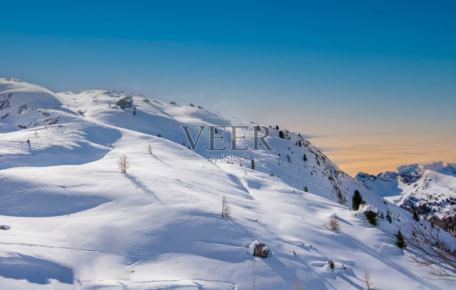 夕阳在白雪皑皑的山峦后落下照片摄影图片