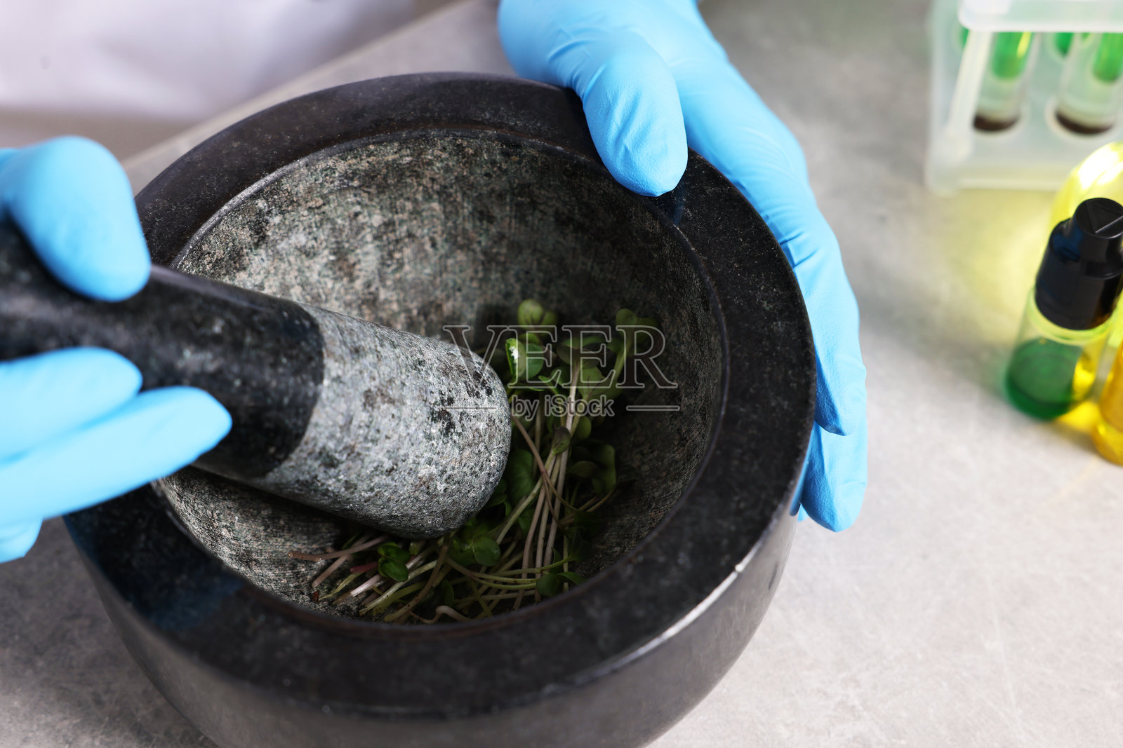 生物化学。科学家在灰色桌子旁用植物和液体工作，特写照片摄影图片