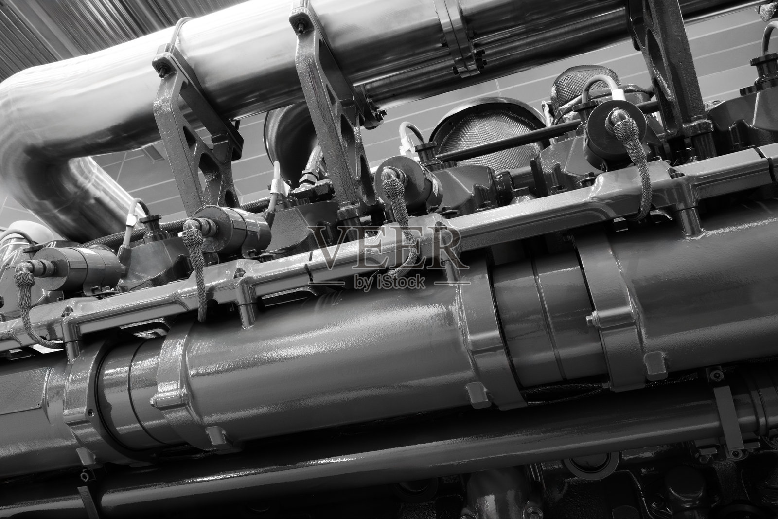 一个大型发动机，包含许多零件。该发动机由金属制成，有许多管道和阀门。象征着工业化和机械的复杂性。照片摄影图片