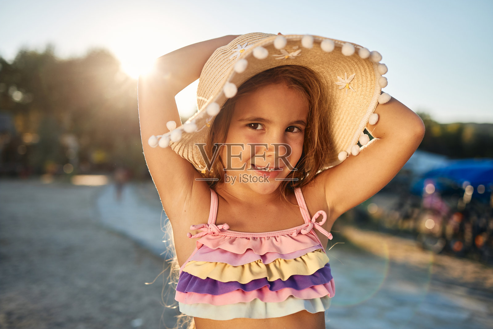 戴着草帽和泳衣在海滩上摆姿势的女孩照片摄影图片