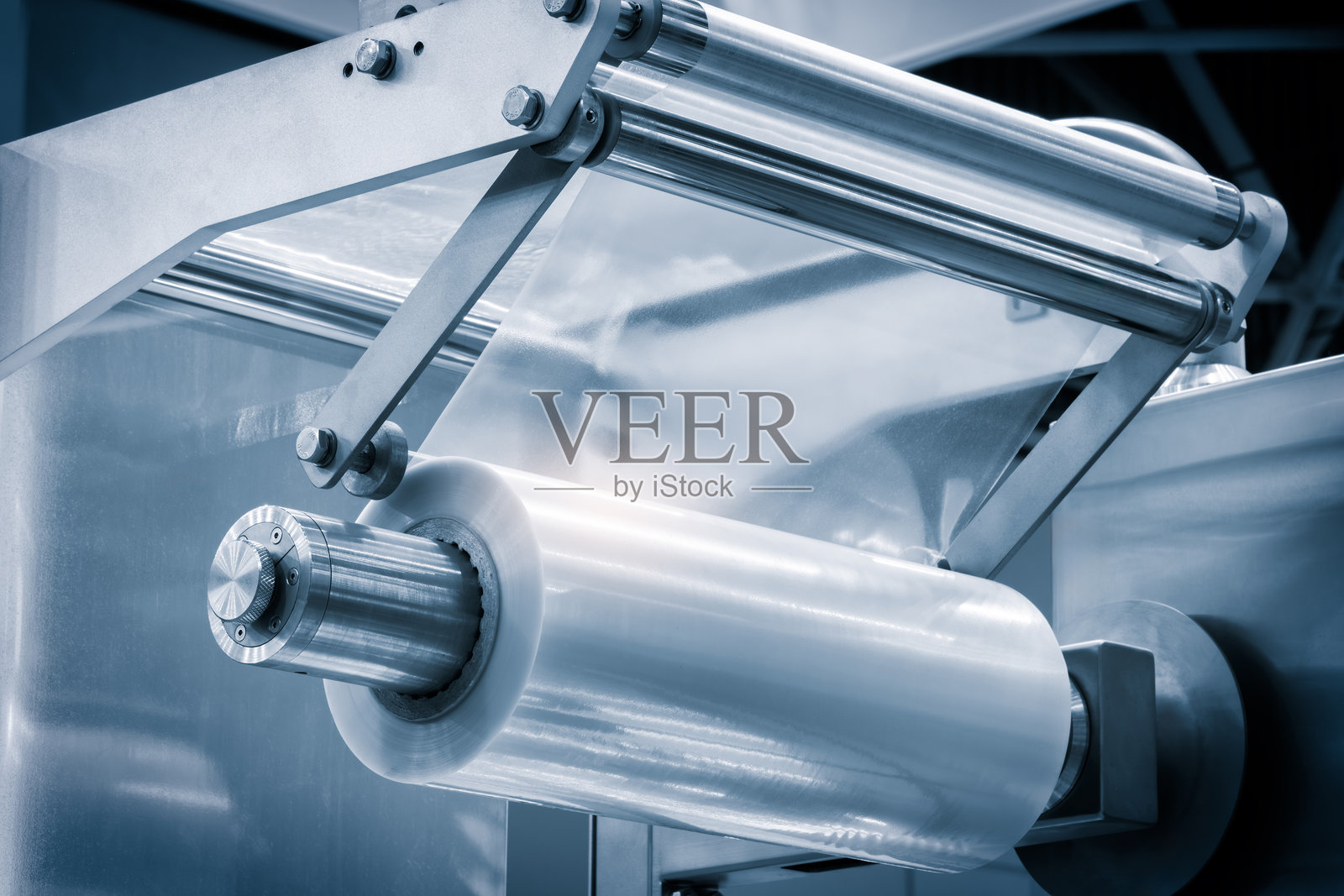 带有灯光效果的自动聚乙烯塑料袋生产机。在浅蓝色场景中，塑料袋生产机滚轮的特写。产品包装概念。照片摄影图片